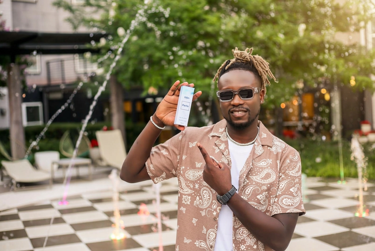 Man holding Perla fragrance in a sunlit city courtyard